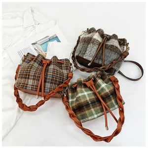 Detail of plaid wool bucket bags featuring woven shoulder straps and drawstring closure