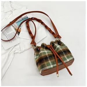 Detail of checkered wool bucket bag with drawstring closure and braided leather strap