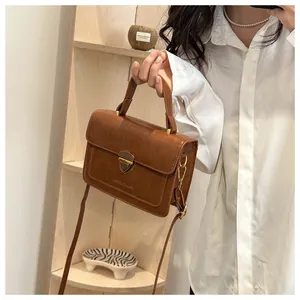 Close-up of brown retro small square bag with golden shield lock and leather handle