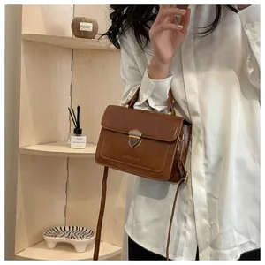 Detail of the vintage brown leather handbag with shield-shaped metal buckle and strap
