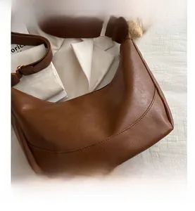 Detailed close-up of brown textured leather crescent bag with stylish metal buckle