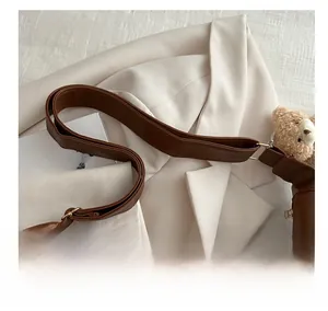 Close-up of the comfortable wide shoulder strap on a brown leather tote with bear charm