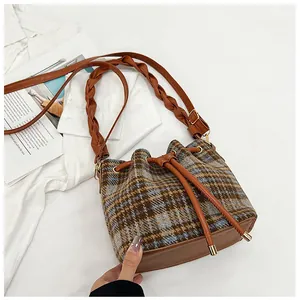 Detail of vintage plaid bucket bag featuring woven strap and drawstring closure