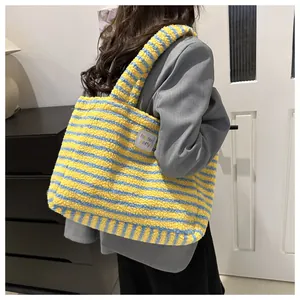 Detail of plush tote bag with yellow and blue stripes featuring a side brand label