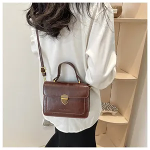 Rear view of a model wearing a retro brown leather crossbody bag with a gold lock