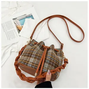 Detail of checkered wool bucket bag with drawstring closure and woven handle