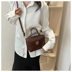 Close-up of the vintage dark brown small square bag with gold shield lock and top handle