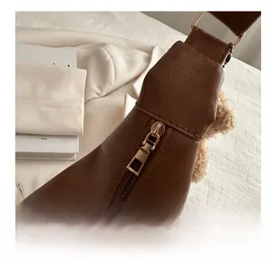 Close-up of golden zipper and hardware on dark brown leather shoulder bag detail