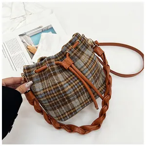 Detail of checkered bucket bag with leather drawstring and thick woven handle strap