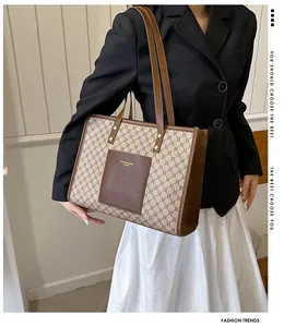 Detailed view of a geometric monogram tote bag with brown leather front pocket on a model