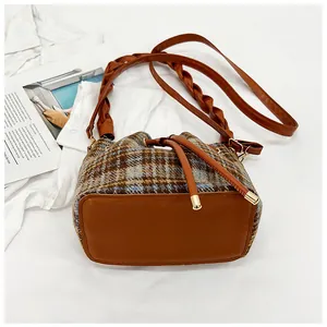 Detail of vintage plaid wool bucket bag with drawstring closure and leather base