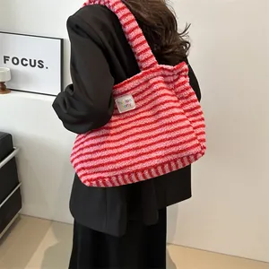 Pink and red striped fuzzy tote bag with soft plush texture worn over a black blazer