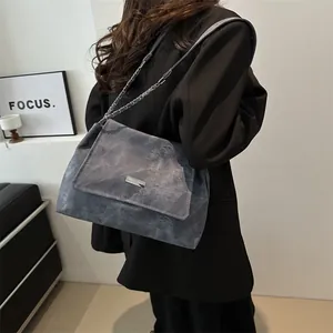 Borsa tote chic grigio marmo con catena d'argento indossata da modella in completo nero