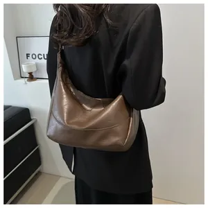 Rear view of model wearing a large brown pebbled leather crescent tote bag for daily commute