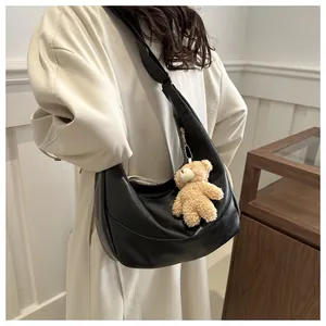 Detail of a black matte soft leather hobo bag featuring a cute plush bear charm accessory