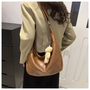 Detail of brown faux leather crescent tote bag with a cute plush bear charm accessory