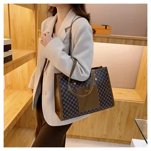 Detail of a large brown geometric tote bag with leather front pocket and slim handles