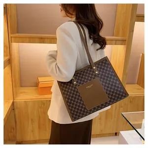 Detail of vintage monogram pattern on tote bag with leather straps and front patch