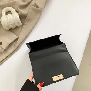 Black matte leather crossbody bag with gold lock shown open on white background