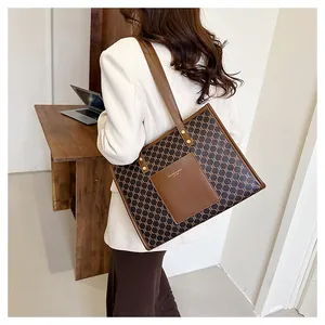 Detail of the large capacity monogram tote bag with leather pocket and gold rivet accents