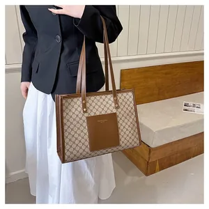 Detailed view of large tote bag with beige monogram canvas and brown leather handles