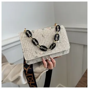 Close-up of floral embroidery on beige woven acrylic bag with wide artistic strap