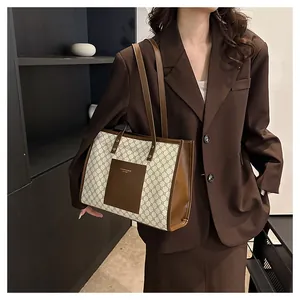Detail of large tote bag with beige geometric pattern and brown leather straps on a model