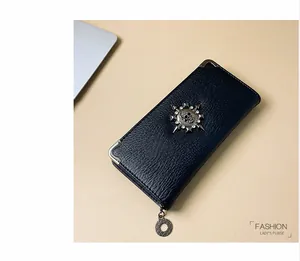 Dettaglio del portafoglio nero in pelle martellata con logo teschio e rivetti borchiati