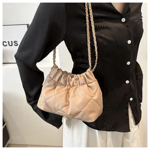 Quilted beige bucket bag featuring a soft cloud-style fold and gold chain shoulder strap