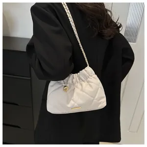 Quilted cream bucket bag with gold chain strap and decorative sphere on black blazer