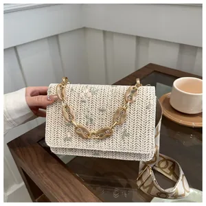 Detail of floral embroidery on cream woven crossbody bag with geometric wide strap