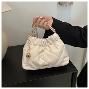 Detail of beige quilted bucket bag showing leather chain strap and gold hardware