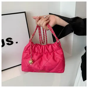 Close-up of quilted fuchsia bucket bag with golden chain and decorative metal ball
