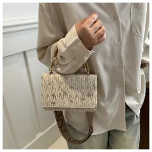 Close-up of floral embroidery on beige woven mini square bag with a wide strap