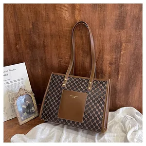Close-up of brown vintage tote bag featuring geometric monogram print and leather pocket