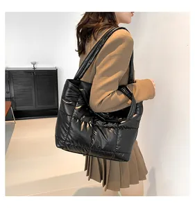 Detailed view of black quilted tote bag with glossy finish on a shoulder model