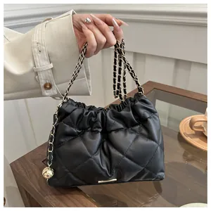 Detail view of quilted black leather bucket bag with gold ball chain strap and textures