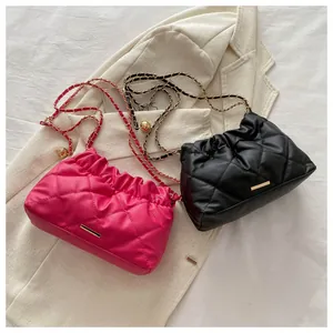 Detail of quilted bucket bags in black and magenta with adjustable gold chain strap