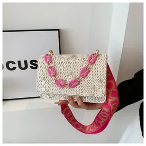 Detail of woven straw handbag with pink floral embroidery and acrylic chain handle