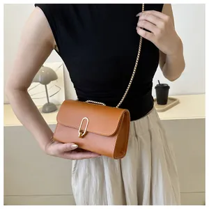 Détail d'un sac bandoulière marron avec surpiqûres blanches et fermoir doré sur mannequin