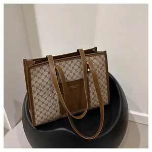 Close-up of vintage monogram canvas tote bag with brown leather straps on a chair