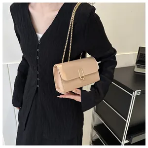 Détail du sac carré en cuir beige avec fermoir en U doré et bandoulière chaîne