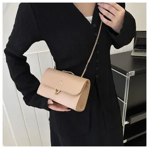Détail du petit sac carré beige avec boucle en U dorée et fine bandoulière chaîne