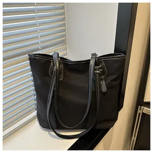 Detail of black tote bag featuring contrast white stitching and premium canvas texture