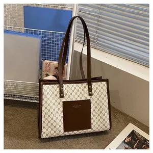 Detail view of large tote bag with geometric pattern and brown leather front pocket