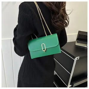 Détail du sac bandoulière vert avec surpiqûres blanches et chaîne dorée chic