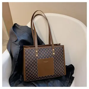 Detail of vintage tote bag with retro monogram pattern and brown leather front pocket