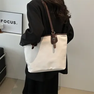 Contrast minimalist canvas tote bag with brown leather trim shown on model shoulder