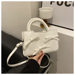 Détail du sac blanc en cuir avec trois nœuds 3D et une poignée semi-circulaire