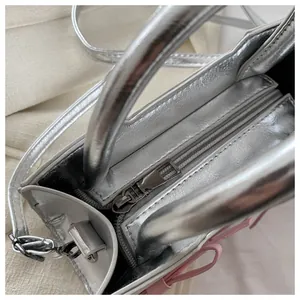 Vue détaillée du sac en cuir verni argenté avec fermeture éclair et doubles anses élégantes